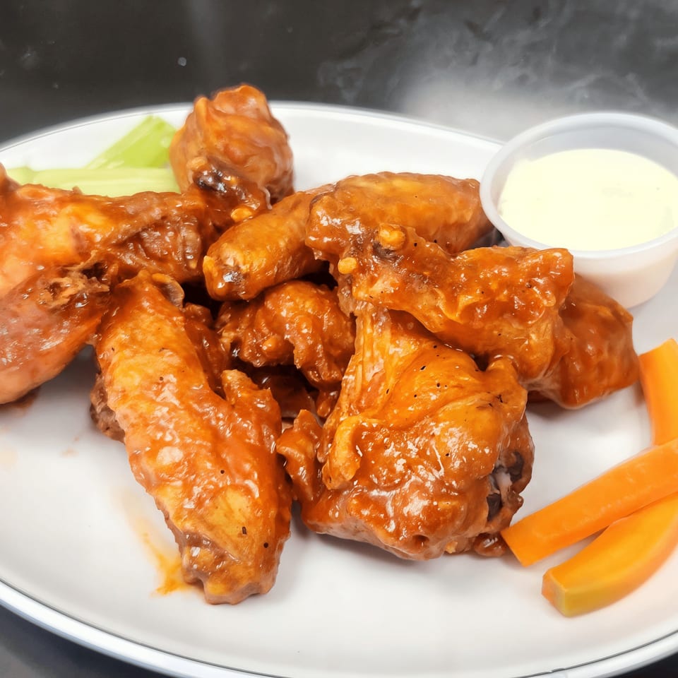 Shorty's American cuisine features a plate of buffalo wings with celery, carrots, and dipping sauce.