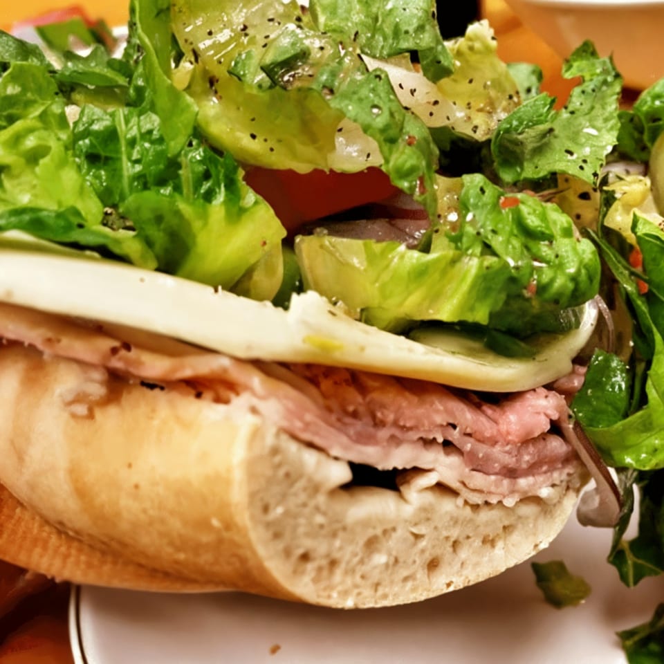 Close-up of a Shorty's American sub sandwich with deli meat, cheese, and a side salad.