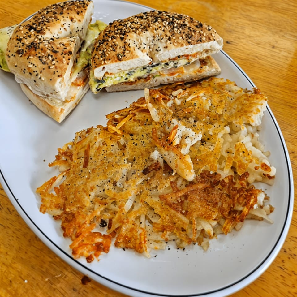 Shorty's cuisine breakfast plate with an everything bagel sandwich and a side of crispy hash browns.