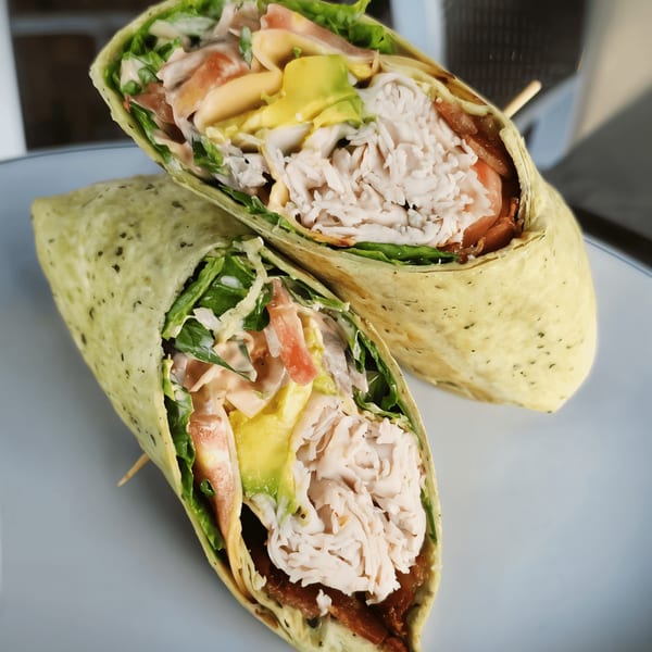 Two halves of a Shorty's turkey and avocado wrap, filled with lettuce, tomato, and sauce.